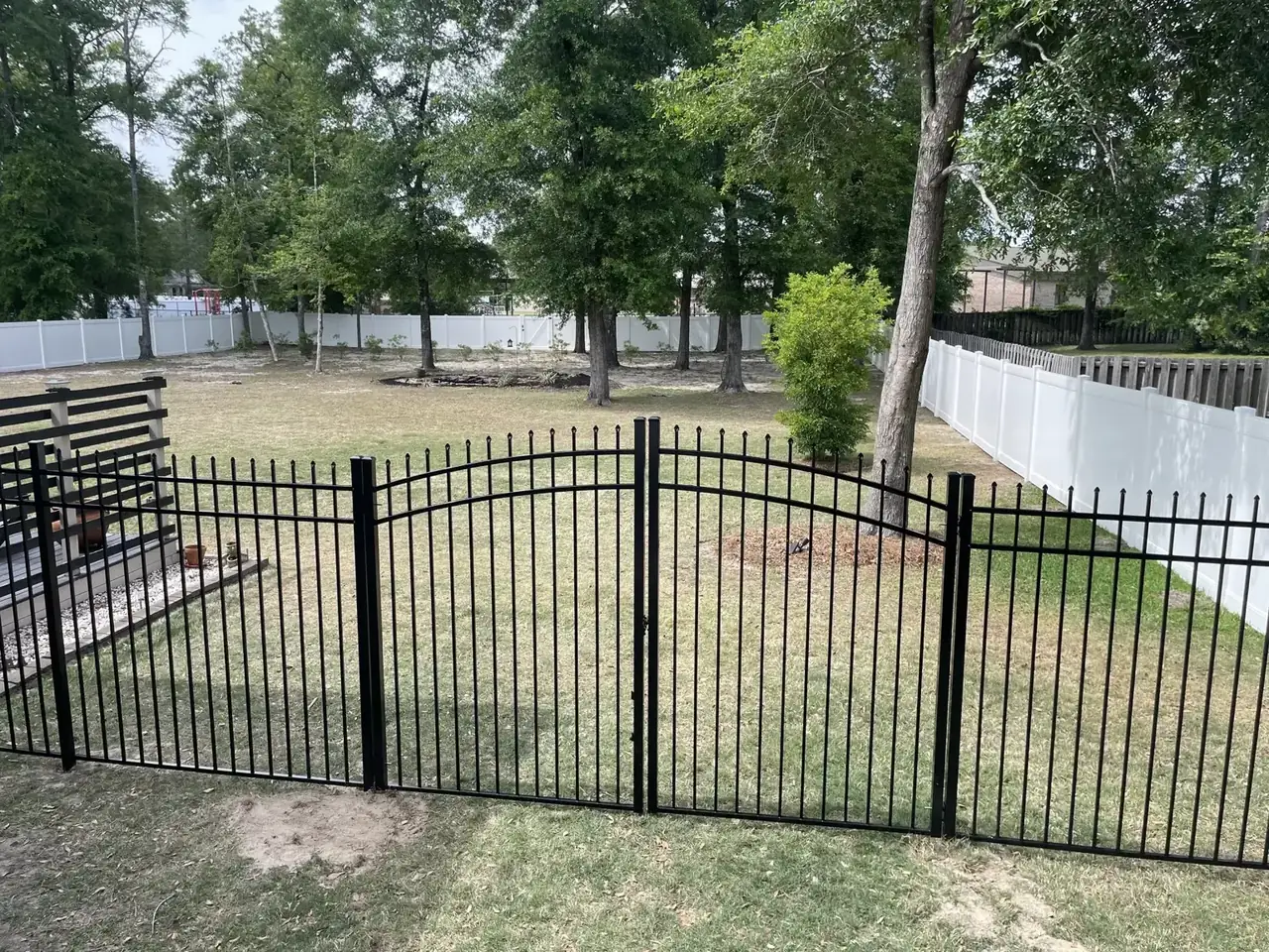Black aluminum gate connected to white vinyl privacy fence