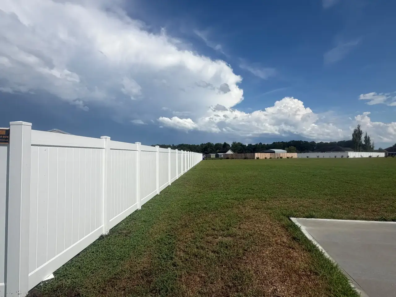 White vinyl privacy fence installed along a large property